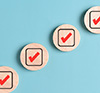 FinAid Article Thumbnail - Hand placing target icon after checkmarks on wooden discs